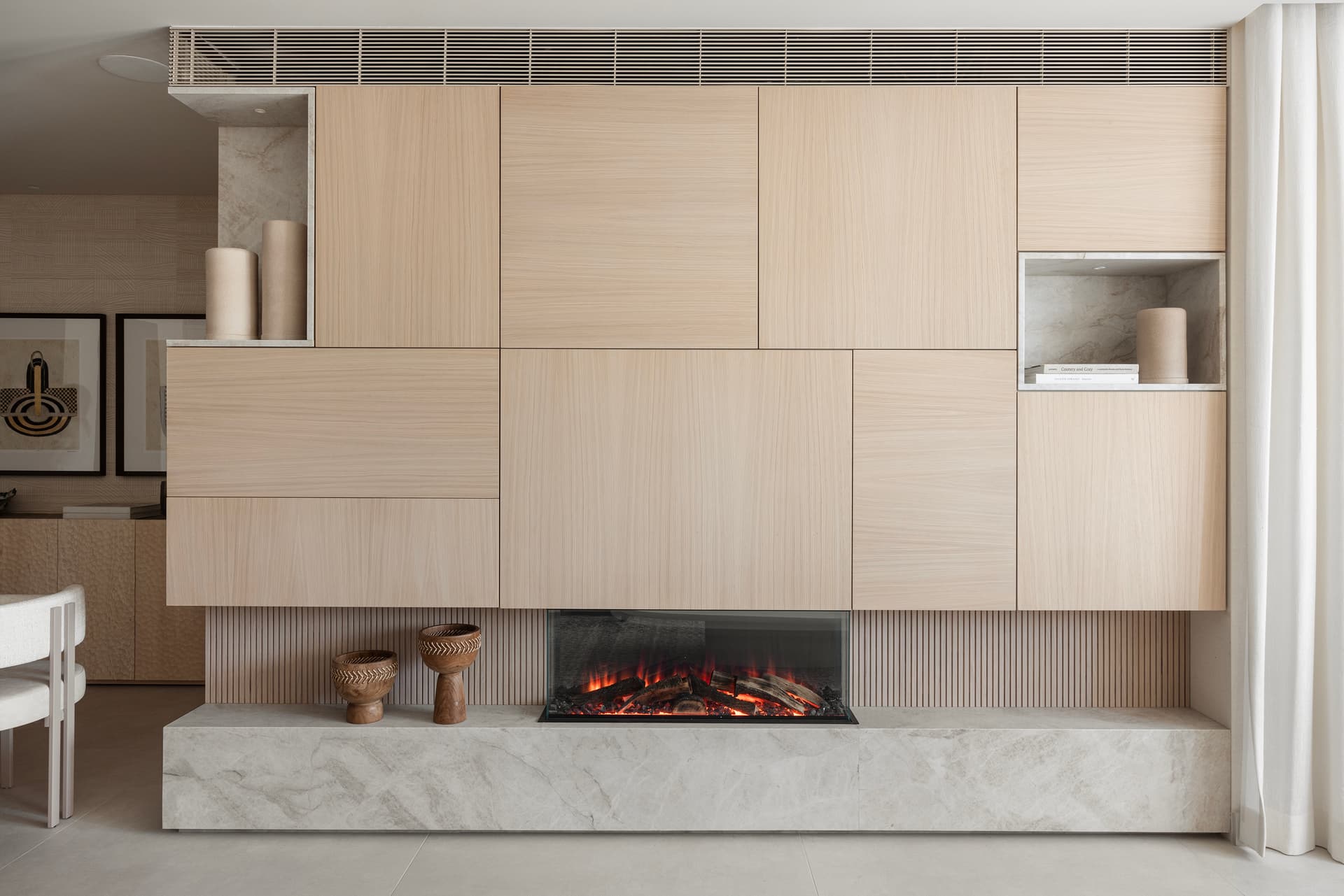 Fireplace wall with floating oak cabinetry and marble hearth