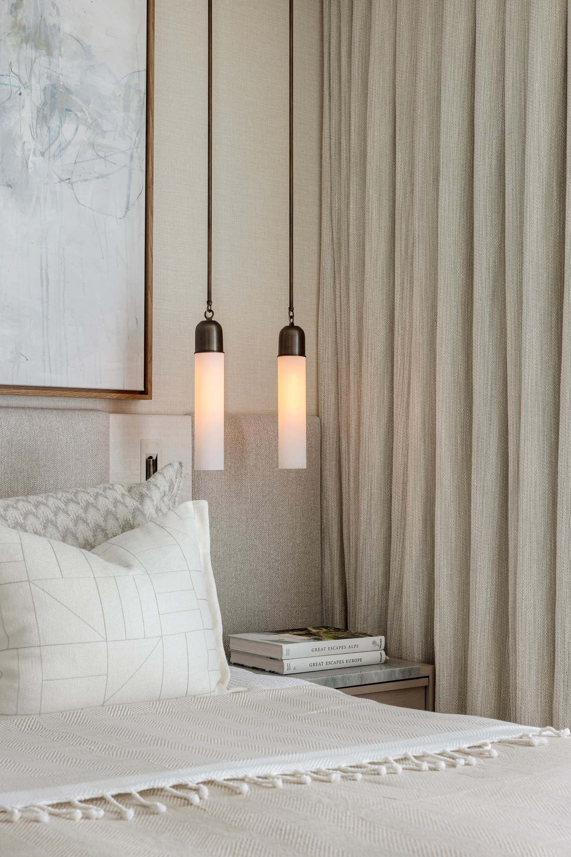 Bedroom pendant lamps glowing warm above nightstand