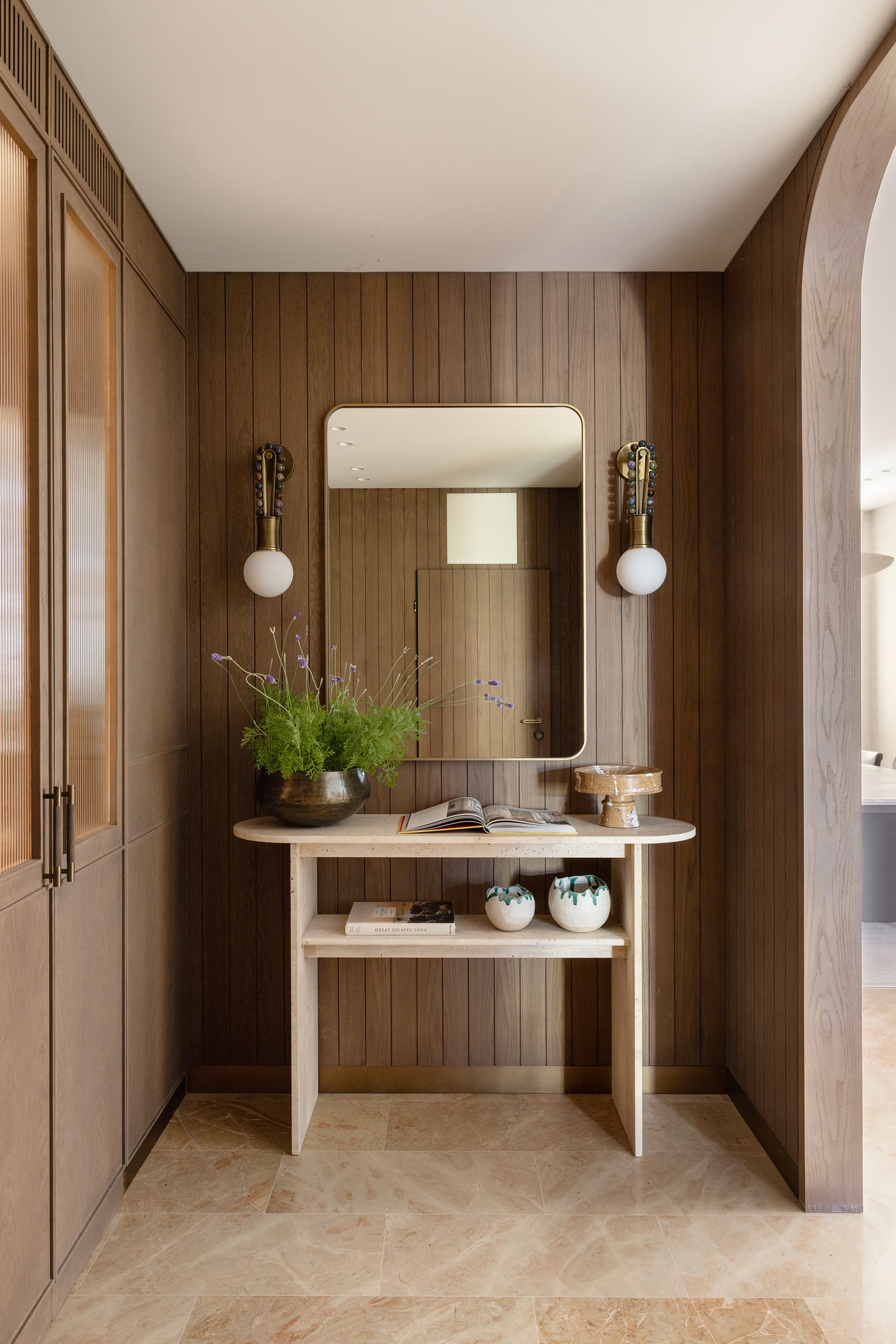 Entry console with brass sconces and travertine floor