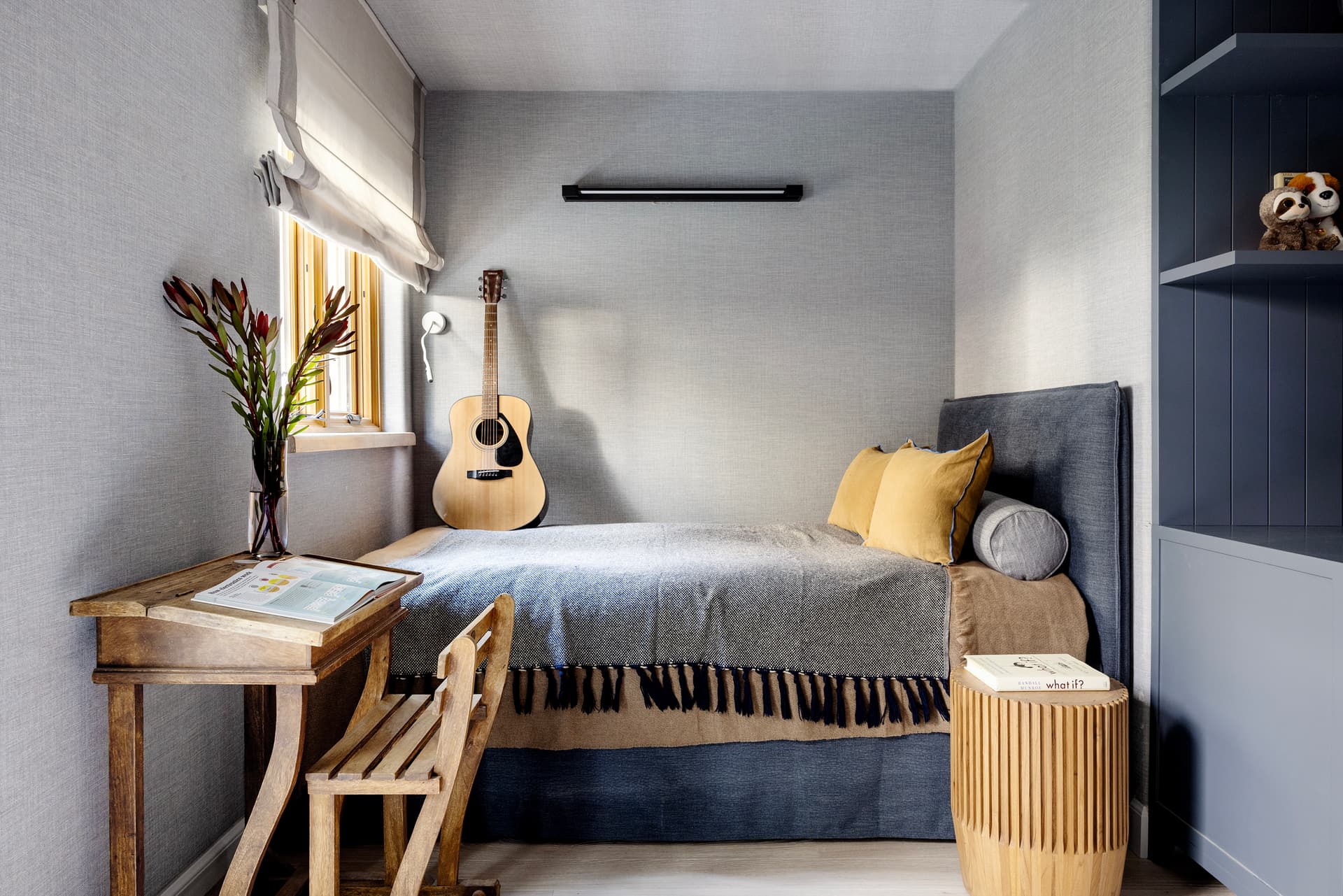 Children's bedroom with guitar, navy cabinetry and wooden desk