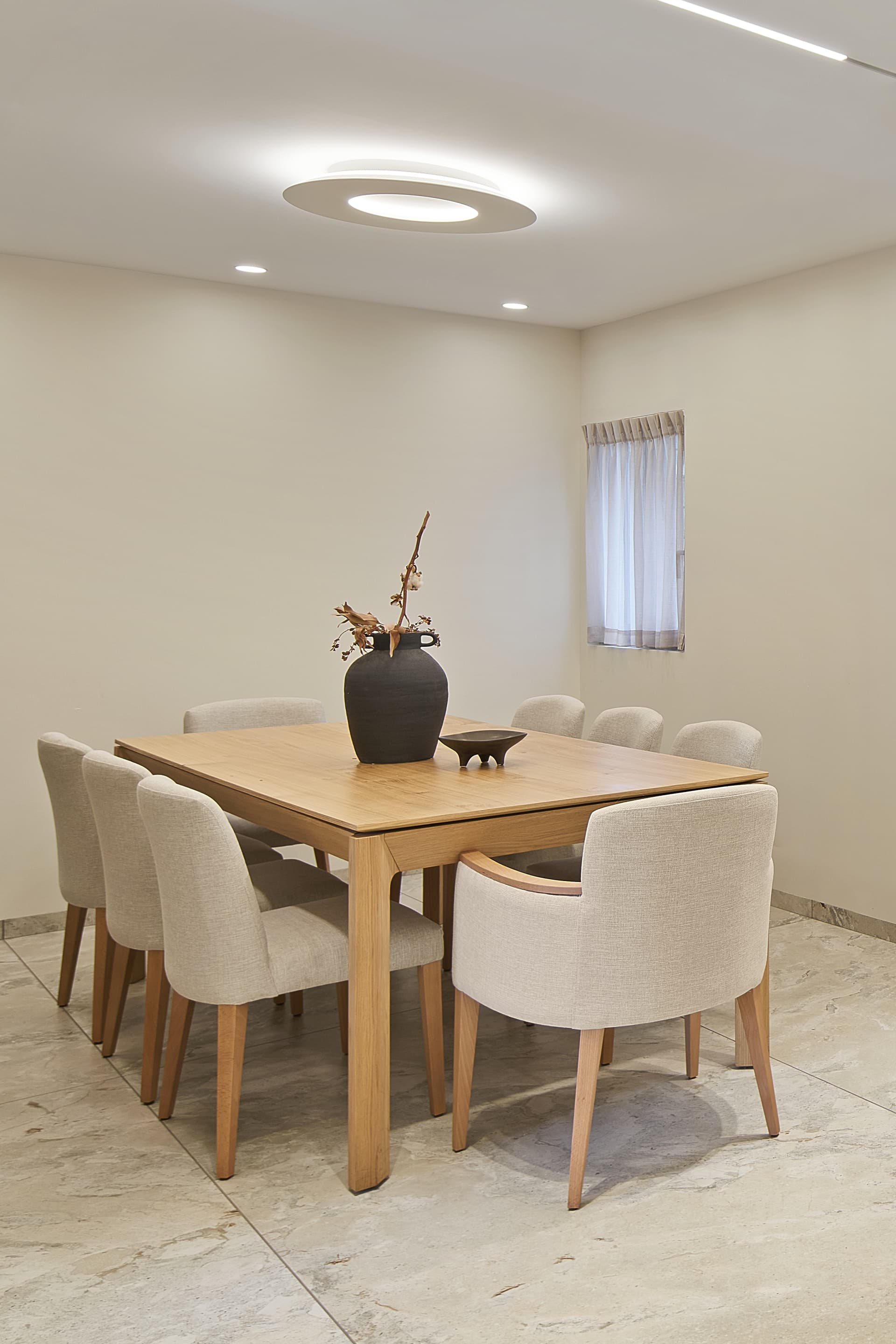 Dining table with upholstered chairs and ceramic vase, warm natural light