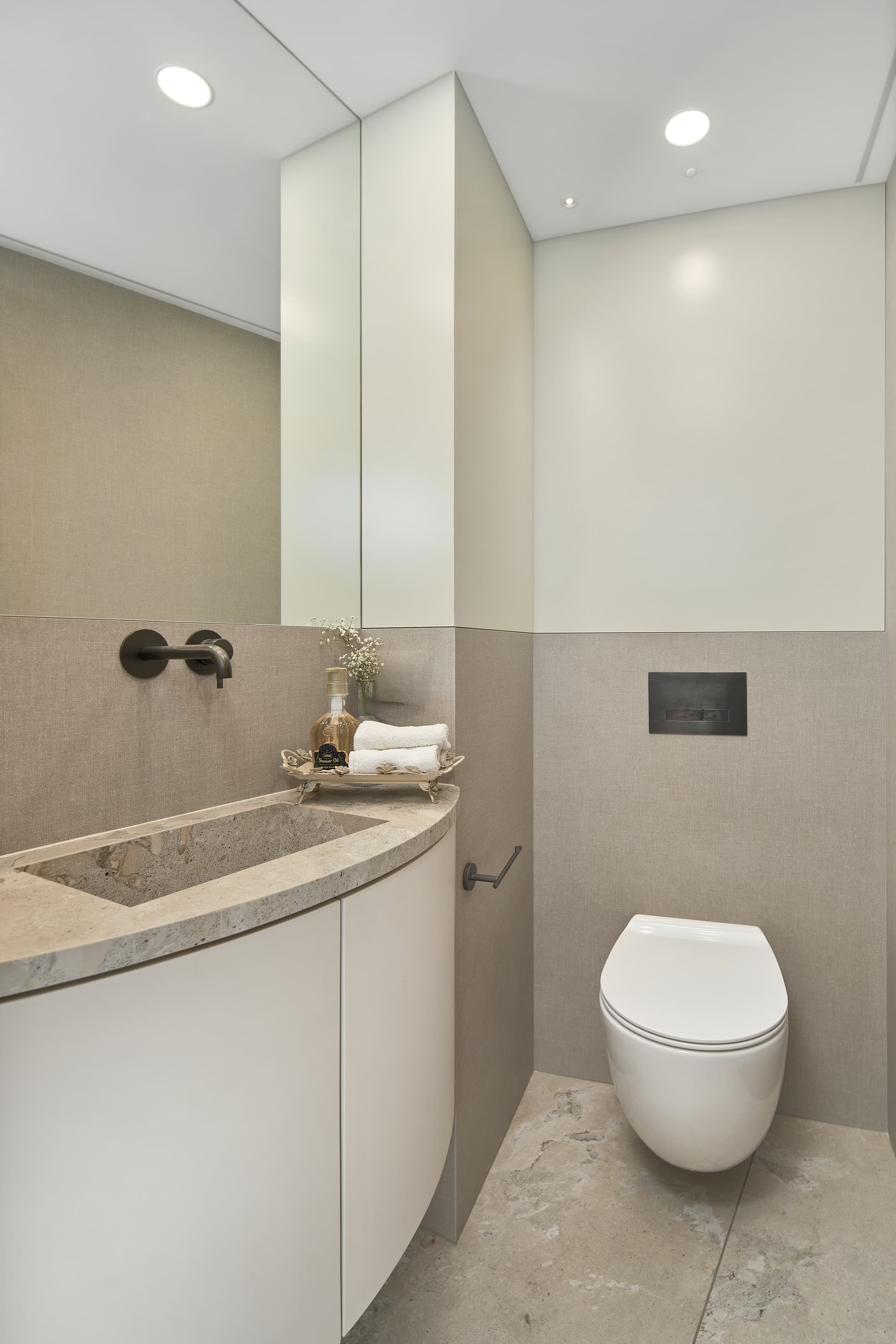 Powder room with curved stone vanity and wall-mount faucet