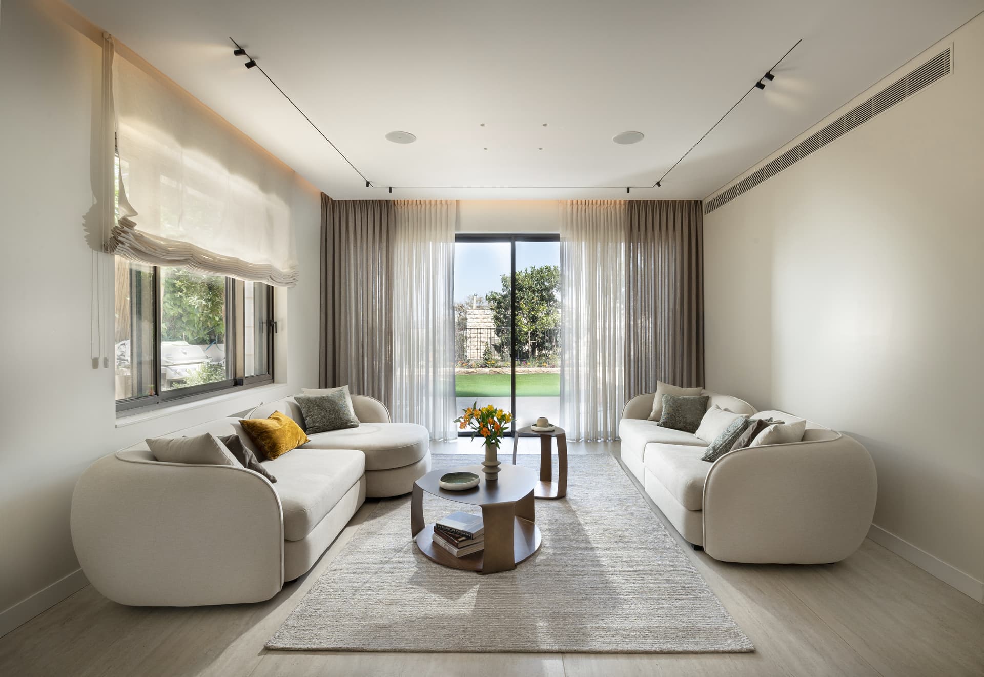 Open living room with two cream curved sofas opening onto a private garden, Ramat Eshkol Triplex Jerusalem