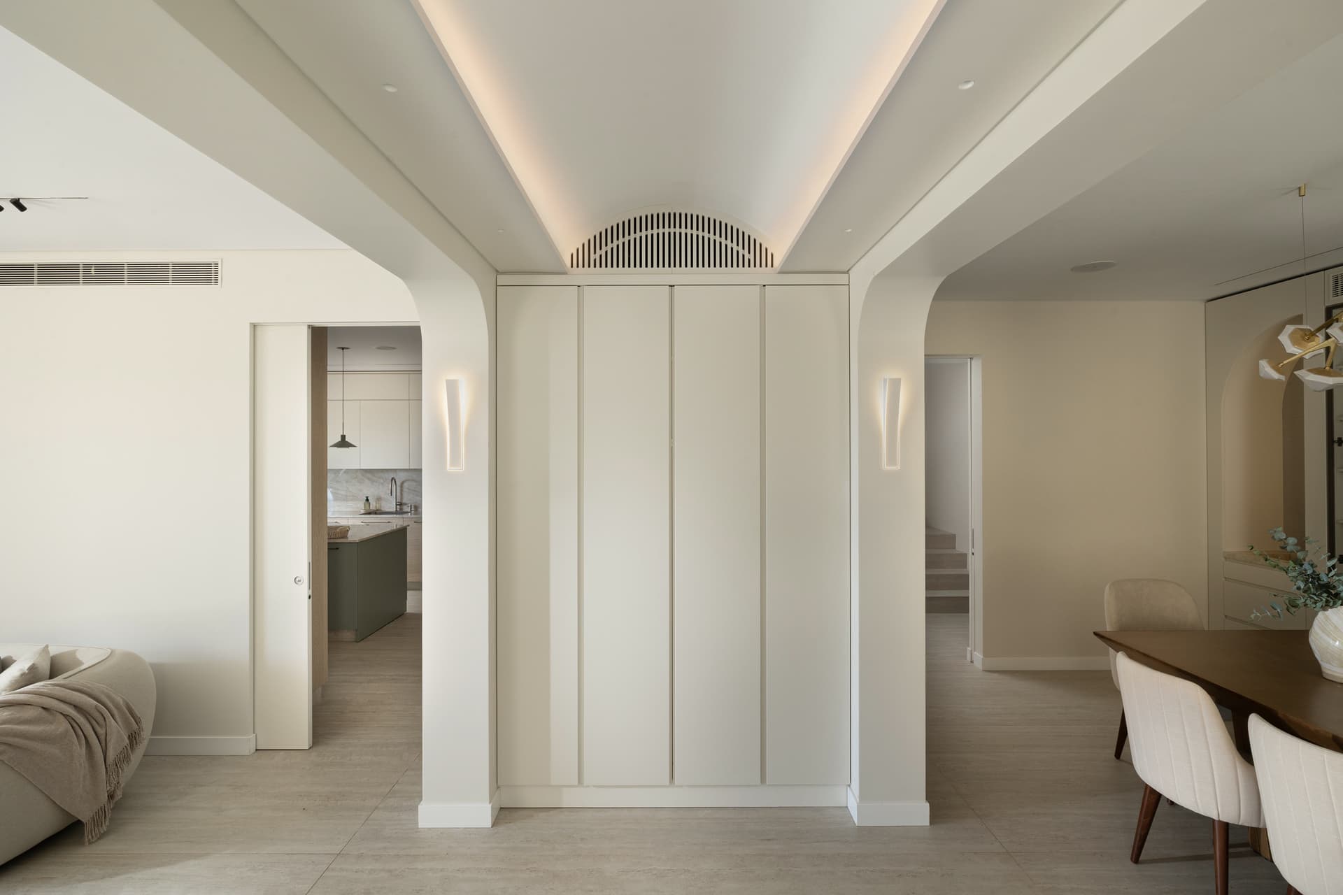 Central foyer with arched openings, recessed cove lighting, and built-in storage joinery