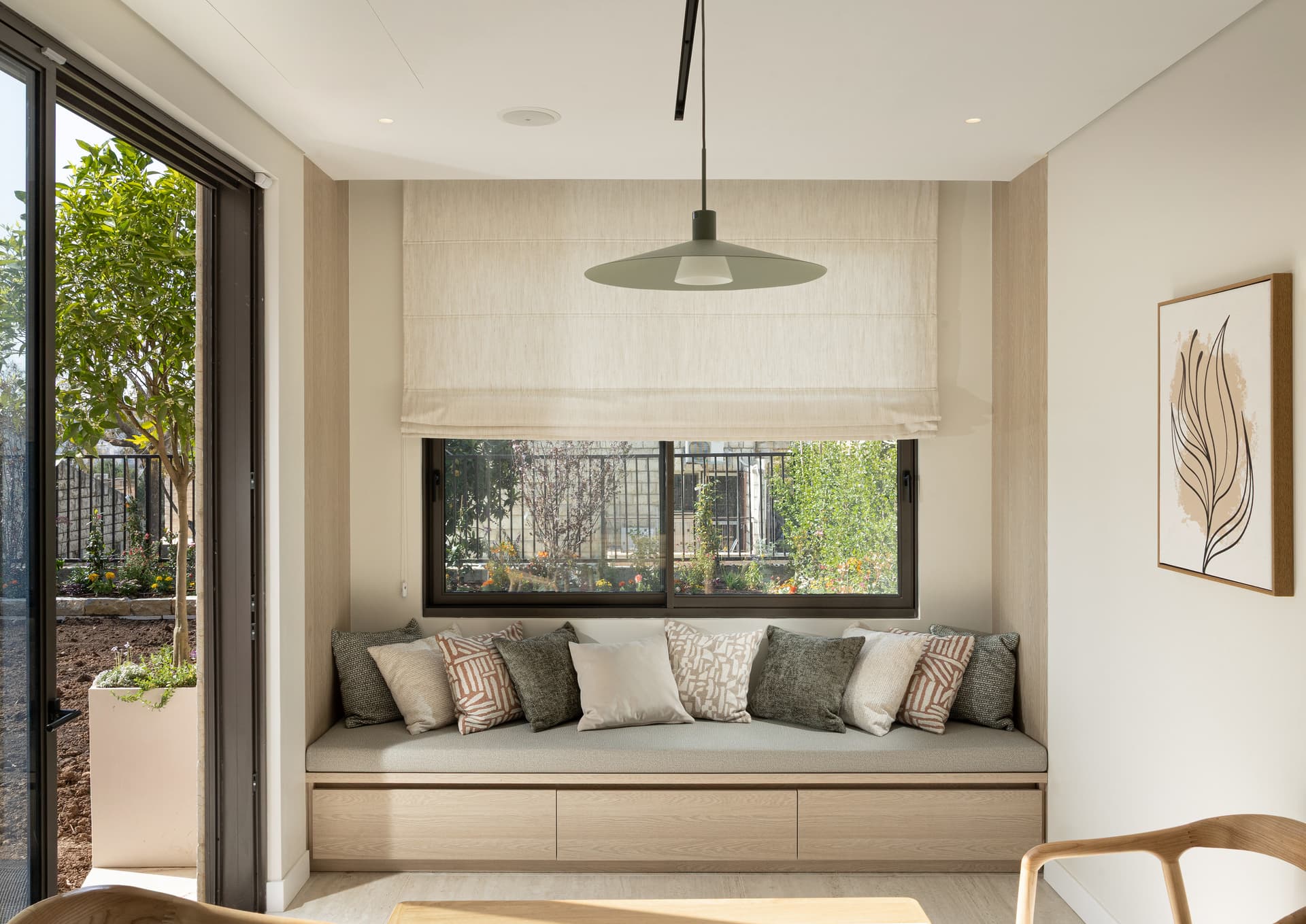 Breakfast nook with window banquette, oak table, woven fruit bowl, and botanical prints