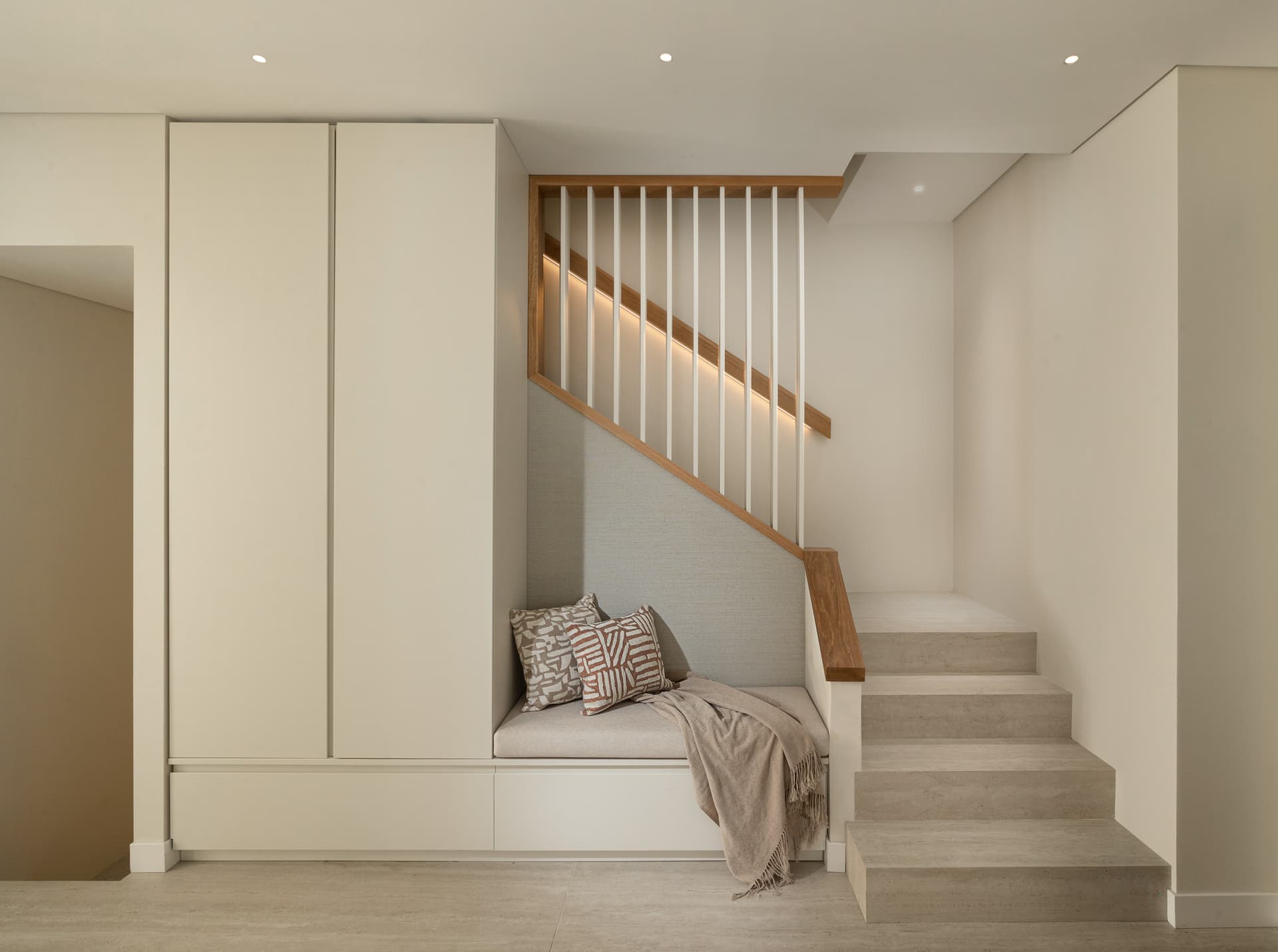 Internal staircase with oak handrail, slatted spindle screen, and built-in reading nook at the landing