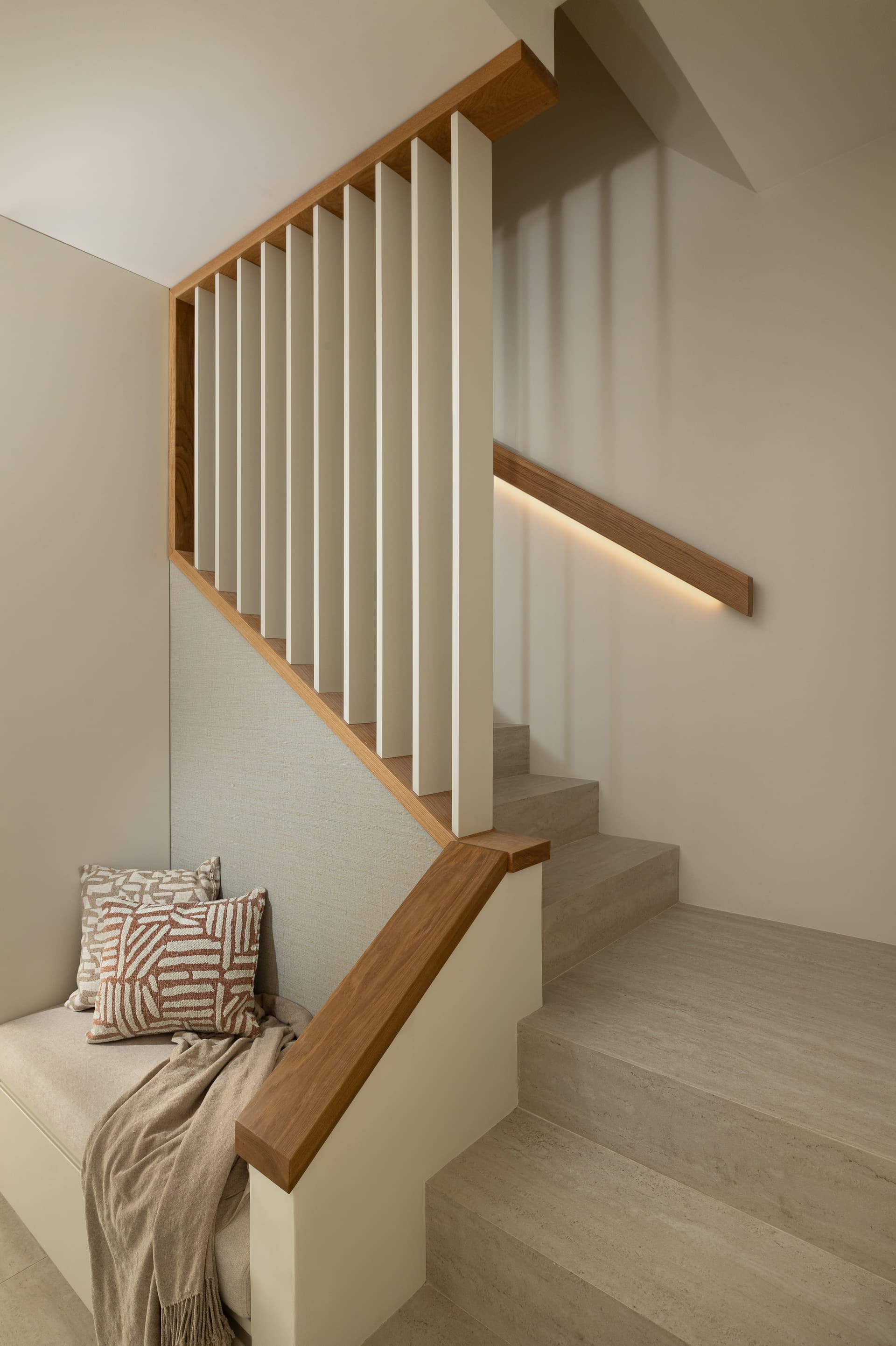 Oak-and-white staircase with under-stair reading bench and LED-lit handrail