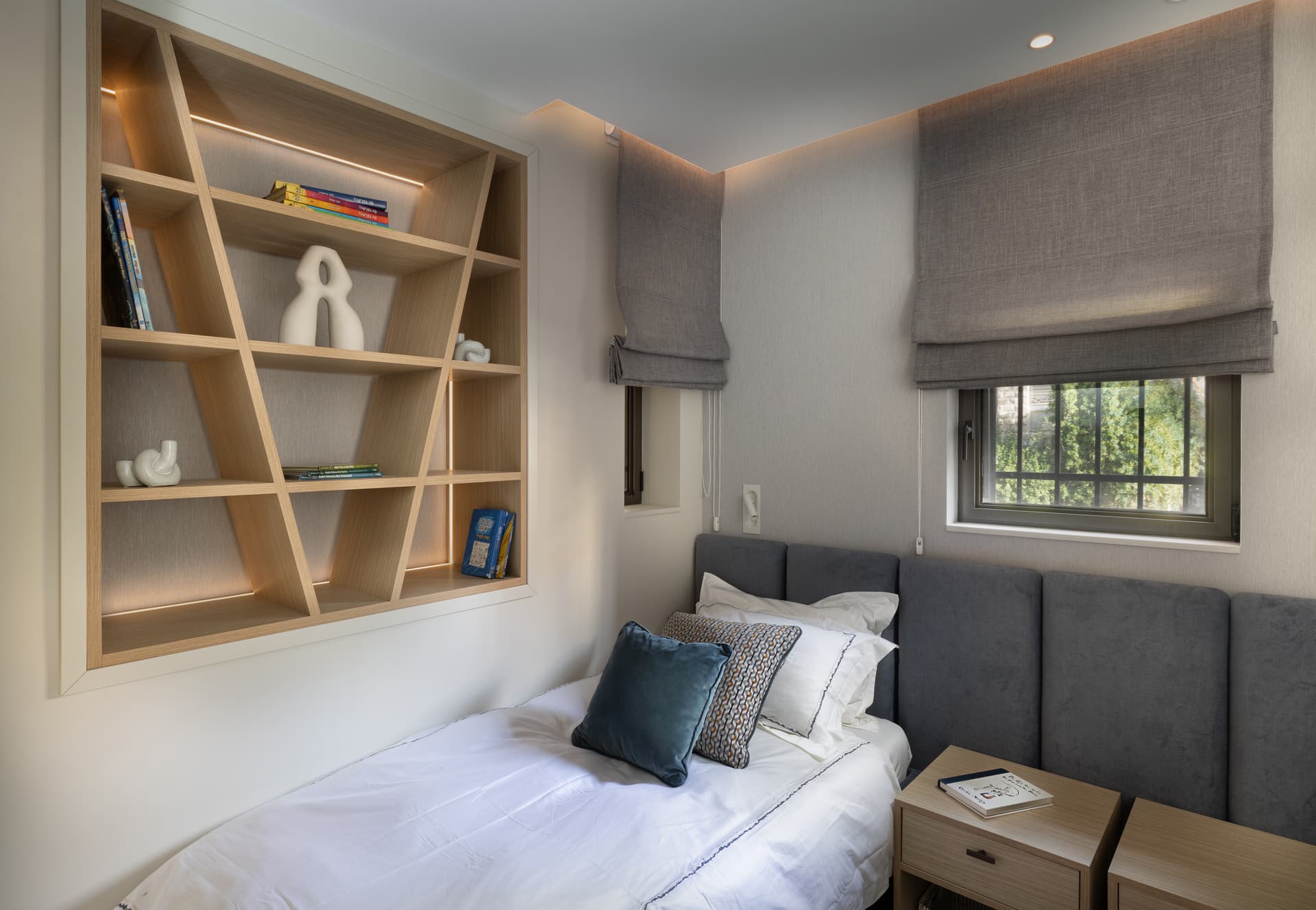 Teen bedroom with channel-stitched grey headboard and angular oak display shelving