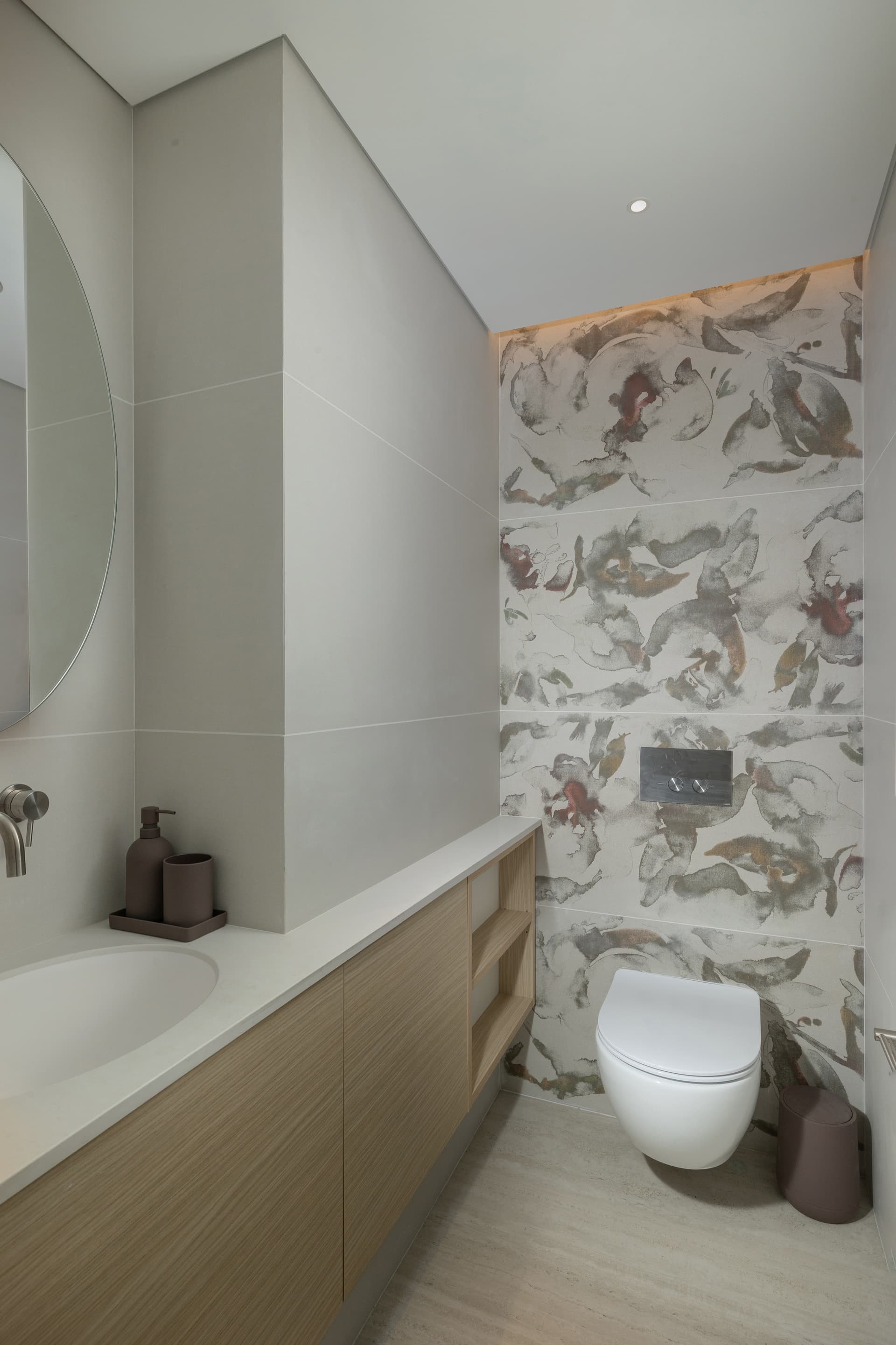 Bath niche detail with olive-patterned tile, towel rail, and eucalyptus in a green glass vase