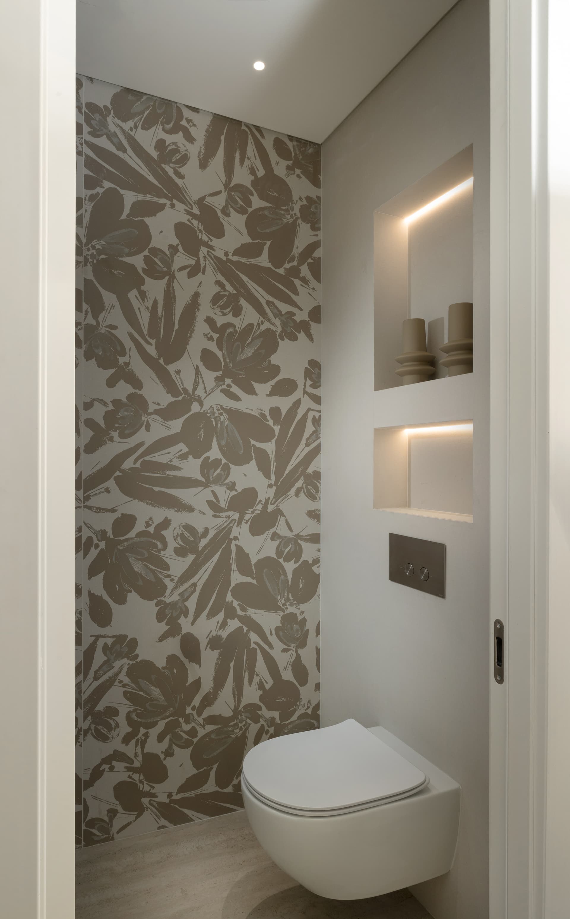 Guest WC with bold botanical-print feature wall and backlit display niches